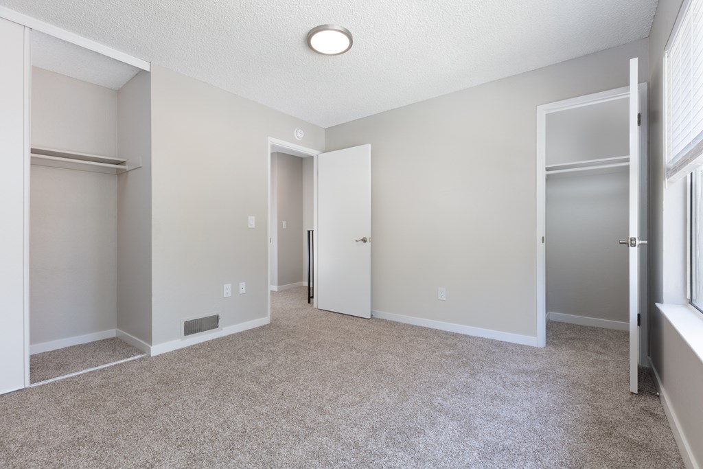 a bedroom with a carpeted floor and a closet with two doors